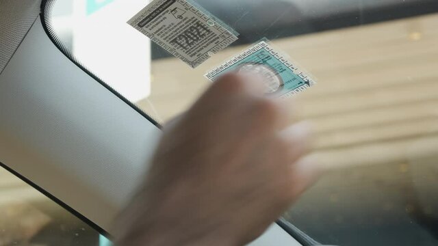A man sticks a toll sticker or vignette on his windshield for traveling abroad for driving highway