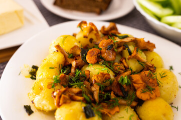 baked  potatoes with chanterelles, served with herbs on white plate