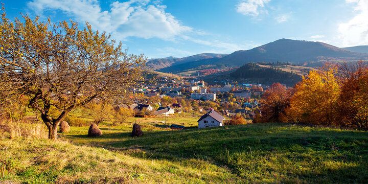 carpathian rural landscape in autumn. village in the valley at the foot of the mountain. beautiful countryside scenery in evening light. trees in fall foliage on the grassy hills