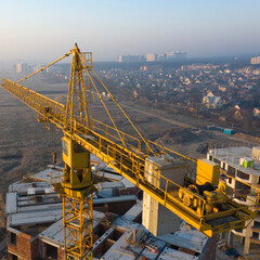 Construction crane on a construction site at dawn. Morning fog on the horizon.