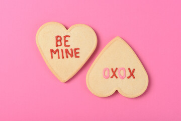 Two Heart Shaped vookies for Valentines Day on pink. Be Mine and XOXO are written in icing on the coolies.