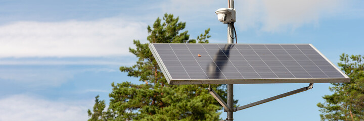 Solar powered surveillance camera. Solar panels powering a surveillance camera in a city park...
