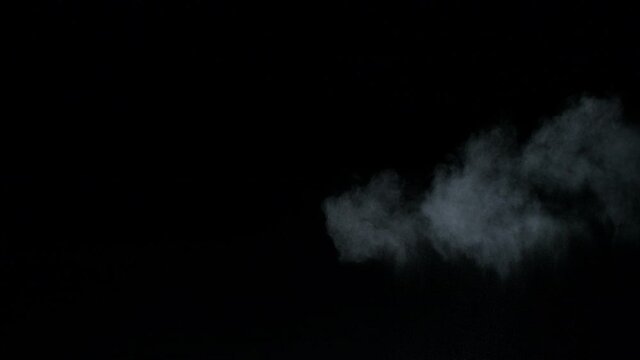 Misty chalk clouds blowing into the center. Isolated super slow motion white smoke and fog wisp on black background. Studio concept and VFX plate shot for scene overlay and creative enhancement.
