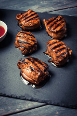 Grilled pork medallions with ketchup served on stone board in rustic style. Vertical orientation.