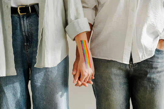 LGBT couples holding hands with rainbow flag symbol on hand. Two bisexual women girlfriends loving each other. Lesbian and LGBTQ comunity concept.