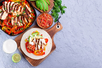 Chicken Fajitas with bell pepper, onion, salsa Asada, avocado and sour cream on soft tortilla, horizontal, top view, copy space