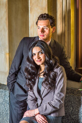 A couple of young businessman and businesswoman are standing outside by a window, talking and taking a break.