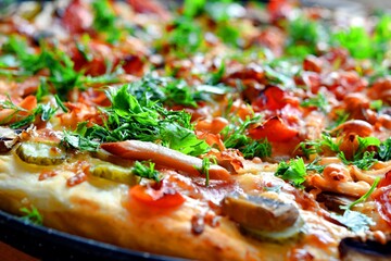 pizza of champignons, tomato, ham, sausages, sprinkled with parsley and homemade dill close-up