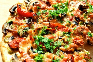 pizza of champignons, tomato, ham, sausages, sprinkled with parsley and homemade dill close-up