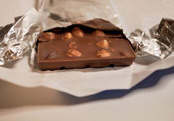 broken hazelnut chocolate close up on white background - swiss chocolate broken in pieces on white background