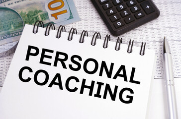 On the table there is money, a calculator and a notebook with the inscription - PERSONAL COACHING
