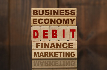 Wooden blocks with the text - Business, Economy, Finance, Marketing and DEBIT
