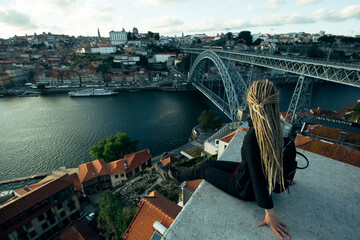 Woman sitting on the viewpoint opposite Dom Luis I bridge over Douro river, Porto, Portugal.