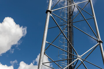 Close up perspective pov of modern metal steel mobile 5g network wireless telecom tower against clear blue sky background on bright day. Microwave signal broadband equipment base line station mast