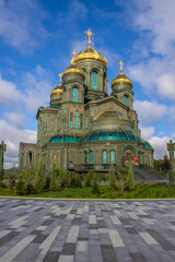 Fototapeta na wymiar facade of the modern main temple of the Russian Armed Forces with golden domes in Patriot Park against a blue cloudy sky in Kubinka Moscow region