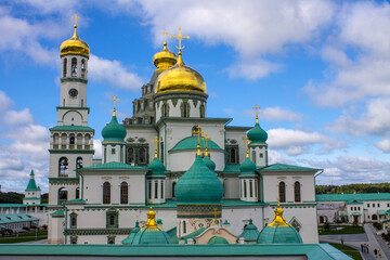 Fototapeta na wymiar beautiful architectural ensemble of white stone churches with golden domes in New Jerusalem on a sunny summer day against a bright blue sky with clouds in Istra Moscow region