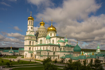 Fototapeta na wymiar beautiful architectural ensemble of white stone churches with golden domes in New Jerusalem on a sunny summer day against a bright blue sky with clouds in Istra Moscow region