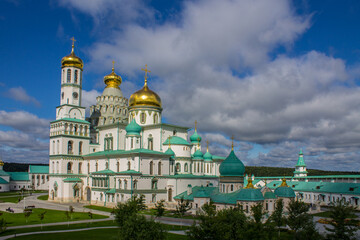 Fototapeta na wymiar a beautiful architectural ensemble of white stone churches with golden domes in New Jerusalem on a sunny summer day against a bright blue sky with clouds