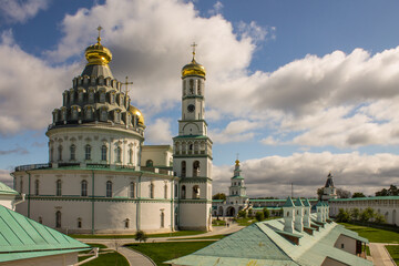 architectural ensemble with the white-stone religious architecture of the New Jerusalem on a sunny bright day and a dramatic blue sky with clouds in Istra Russia