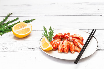 Seafood salad with crab meat and rosemary sprigs and lemon on a white wooden board