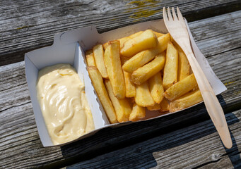 Paper box with french fried potato sticks served outdoor