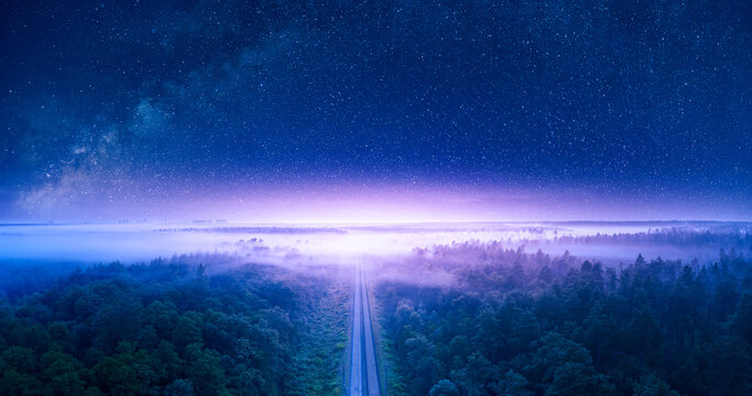 Starry sky over forest and railway view from drone