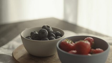 fresh blueberries and strawberries in ceramic bowls with natural light