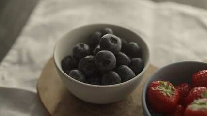 fresh blueberries and strawberries in ceramic bowls with natural light