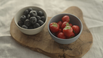 fresh blueberries and strawberries in ceramic bowls with natural light