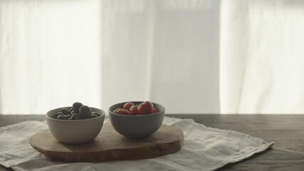 fresh blueberries and strawberries in ceramic bowls with natural light