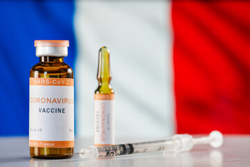 A vaccine against the COVID-19 coronavirus and a medical syringe on background of French flag. The...
