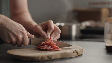 man slicing salami on olive board
