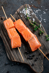 Raw salmon skewers for grilling in the Asian style on wooden board. Seafood barbecue Recipe