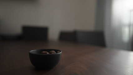 chocolate covered pistachios in black bowl on walnut table
