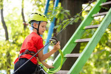 Naklejka premium Cute school boy enjoying a sunny day in a climbing adventure activity park