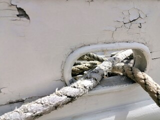 Detail of an old frayed ship's rope tied to an old ship.