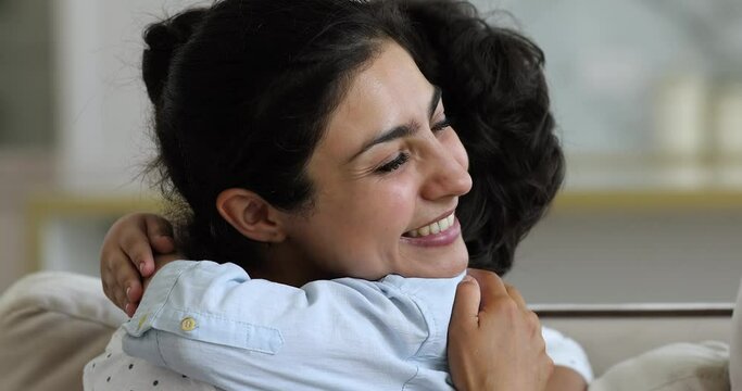 Young loving affectionate Indian ethnicity mother cuddling tightly little cute son, close up view. Happy motherhood, adopted child, foster and custody, parental protection and family bonding concept