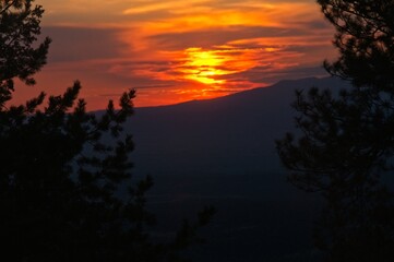 A New Mexico sunrise sets the clouds on fire as it rises above a distance mountain.
