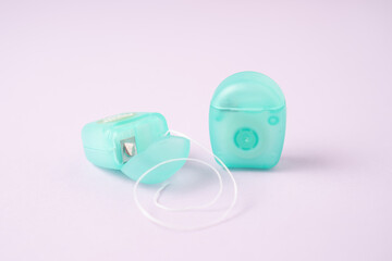 Travel containers with dental floss. Mint dental floss case isolated. Open dental floss containers on violet background