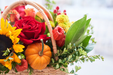 Close-up of a basket with beautiful autumn flowers made of red roses, sunflowers and green leaves. The concept of the holiday. Copy space High quality photo