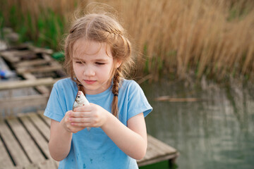 kid girl holding fish that she had just caught in river.fishing with children