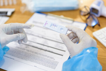 Hand of doctor or nurses holding rapid antigen test kit of Patient for coronavirus, COVID-19 while examination on desk office at hospital, Infirmary, Disease and Public Health service concept.
