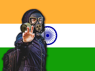 A girl in a black gas mask and dark clothes against the background of the flag of India, a state...