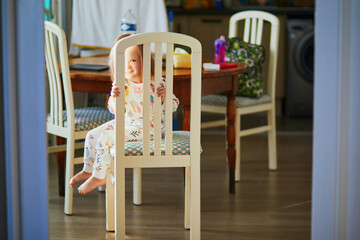 Little girl sitting on the chair at home and playing hide and seek