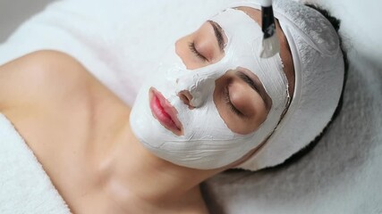 Video of cosmetologist applying the alginates facial mask to woman while lying on a stretcher in the spa center.