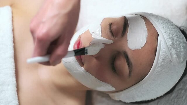 Video of cosmetologist applying the alginates facial mask to woman while lying on a stretcher in the spa center.