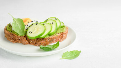 bread toast with cucumber, egg and basil on a plate