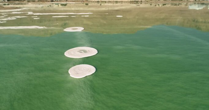 Aerial view of circle salt formation in the colourful water of Dead sea and the salt sea floor. Dead sea, Negev, Israel.