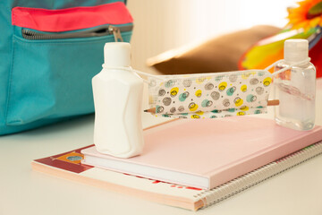 School supplies, hand sanitizer and mask in school bag on table