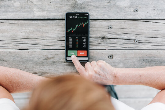 Top view of senior woman using investment mobile phone app to buy crypto currencies - Stock market investment and trading cryptocurrency on app concept 